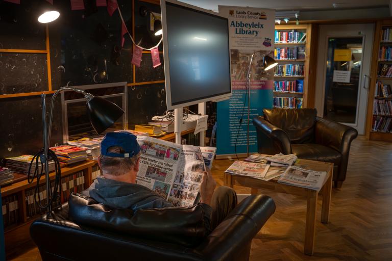 Man reading a newspaper in library