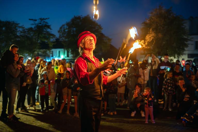 Image of man juggling 3 sticks with fire on end of them.