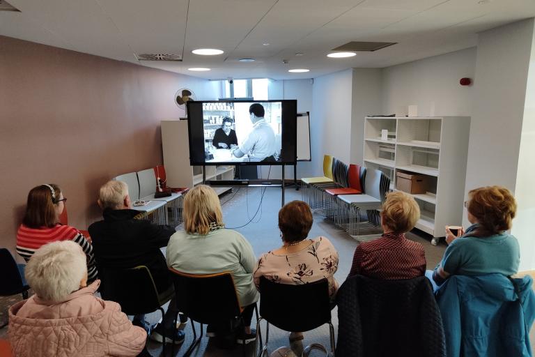 People viewing a film in the library