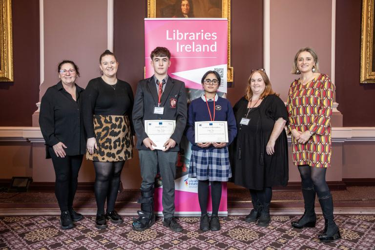 2 students with certificates with 4 women presenting