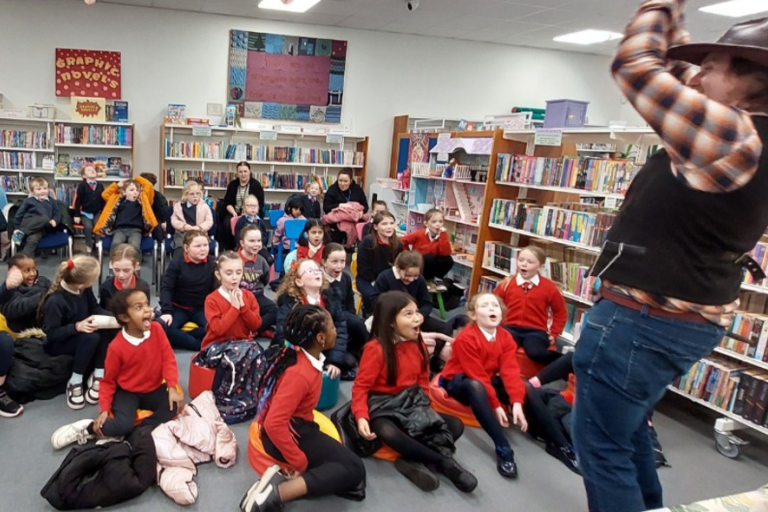 School children watching a man in library