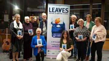 Group of people posing with book in library