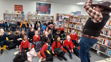 School children watching a man in library