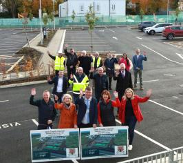 People who were involved in the build smiling and waving in the car park up at a drone